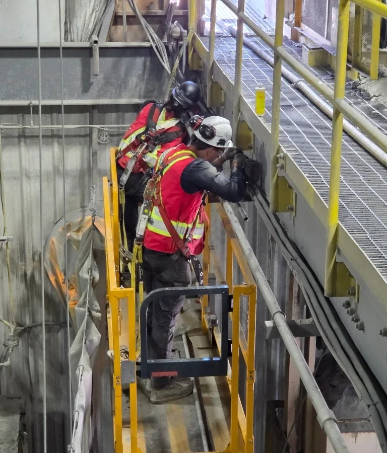 Electrical construction crew on a scissor lift installing conduit and cable in an industrial plant